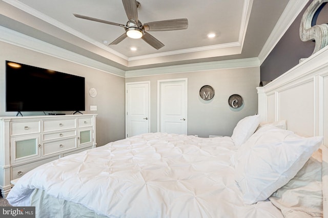 bedroom featuring ceiling fan, ornamental molding, and a tray ceiling