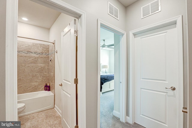 bathroom with toilet, tiled shower / bath combo, and ceiling fan