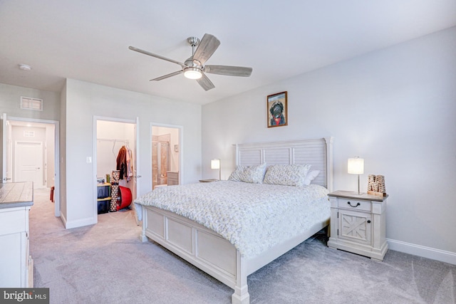 carpeted bedroom featuring a walk in closet, a closet, and ceiling fan