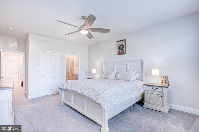 bedroom with light carpet, ensuite bathroom, and ceiling fan