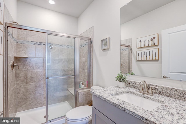 bathroom featuring vanity, a shower with shower door, and toilet