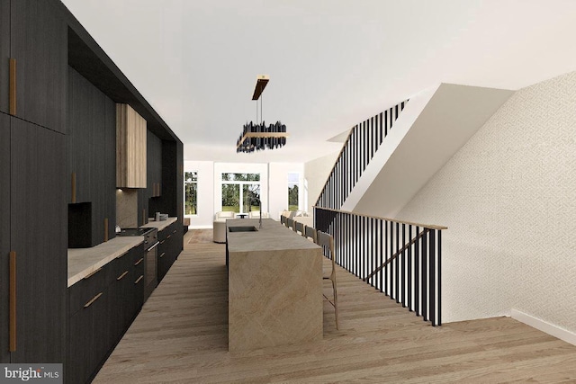 kitchen with a breakfast bar, a center island, hanging light fixtures, and light hardwood / wood-style floors