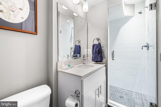 bathroom with toilet, vanity, and a shower with door