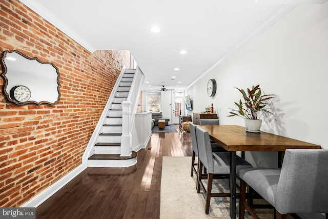 dining room featuring ornamental molding, brick wall, hardwood / wood-style flooring, and ceiling fan