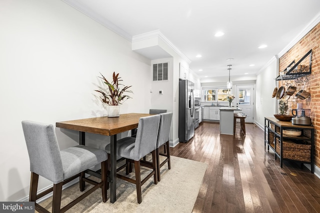 dining area with ornamental molding, dark wood-type flooring, and brick wall