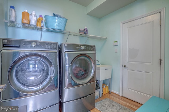 washroom with washing machine and clothes dryer and light hardwood / wood-style floors