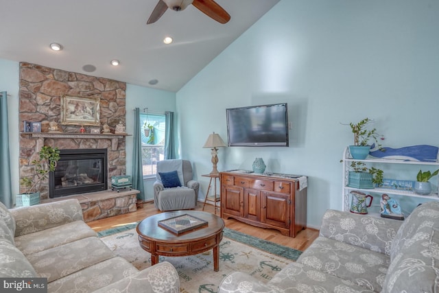 living room featuring a stone fireplace, ceiling fan, high vaulted ceiling, and light hardwood / wood-style floors