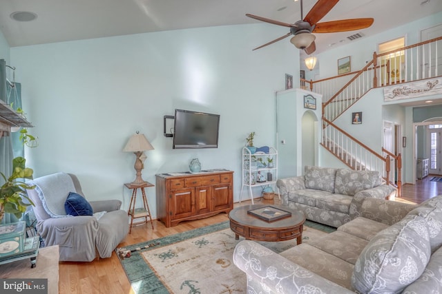 living room with high vaulted ceiling, ceiling fan, and light hardwood / wood-style flooring