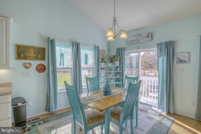 dining space featuring an inviting chandelier, light hardwood / wood-style flooring, and high vaulted ceiling