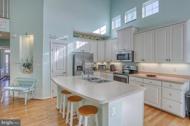 kitchen featuring a high ceiling, white cabinetry, sink, and stainless steel appliances