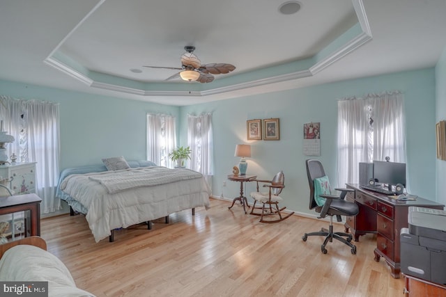 bedroom featuring light hardwood / wood-style floors, ceiling fan, and a raised ceiling