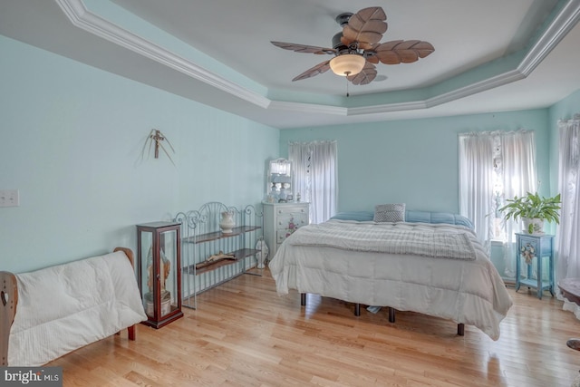 bedroom featuring light hardwood / wood-style floors, ceiling fan, and a raised ceiling