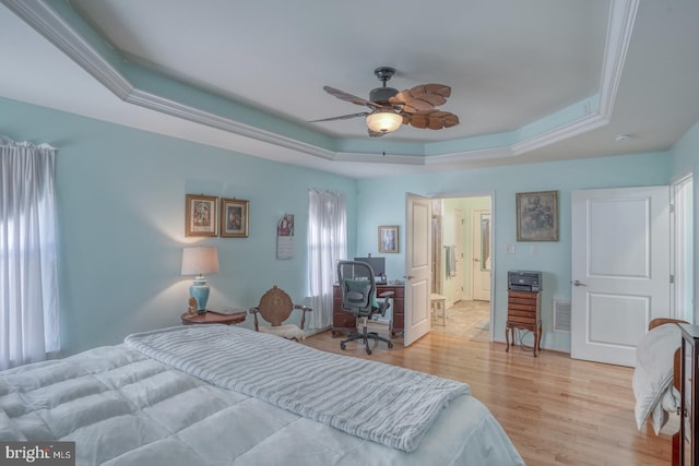 bedroom with light hardwood / wood-style floors, ceiling fan, and a tray ceiling