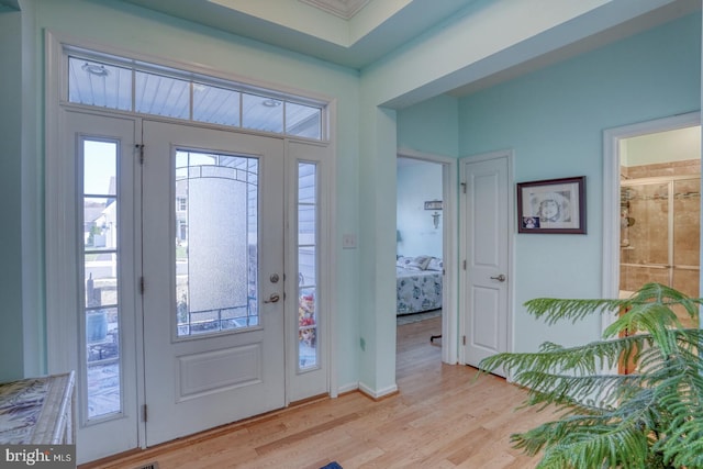 foyer featuring plenty of natural light, light wood-type flooring, and ornamental molding