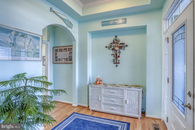 foyer with ornamental molding and light wood-type flooring