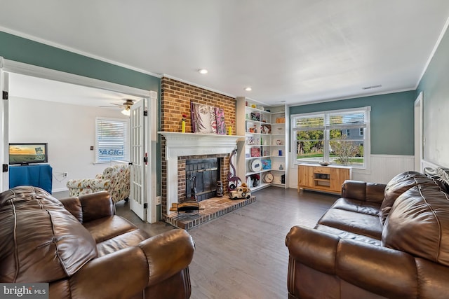 living room featuring a fireplace, built in features, hardwood / wood-style floors, ceiling fan, and ornamental molding