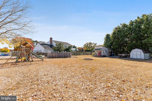 view of yard with a storage unit, a playground, and a fire pit