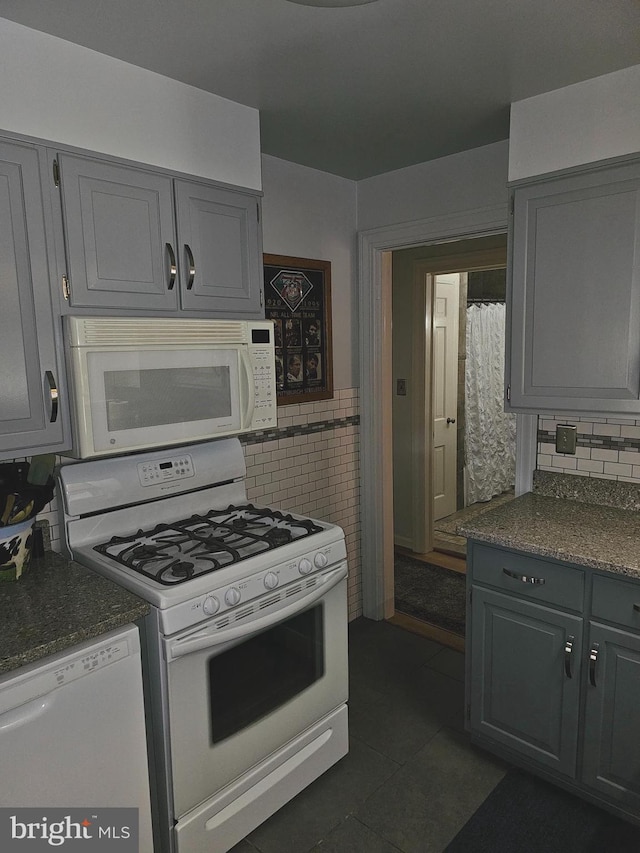 kitchen featuring gray cabinets, dark tile patterned flooring, and white appliances