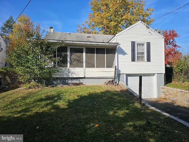 back of property with a sunroom, a garage, and a yard