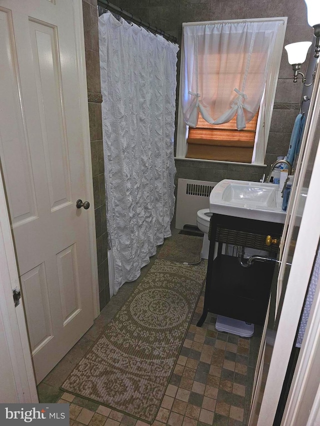 bathroom featuring radiator, curtained shower, vanity, and toilet