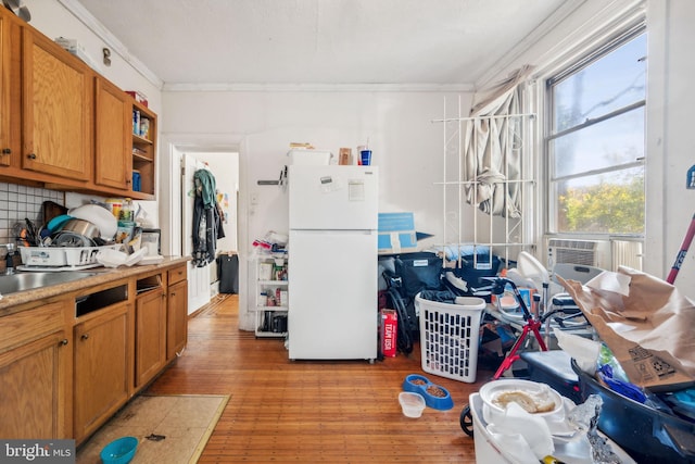 kitchen with decorative backsplash, light hardwood / wood-style flooring, ornamental molding, and white fridge