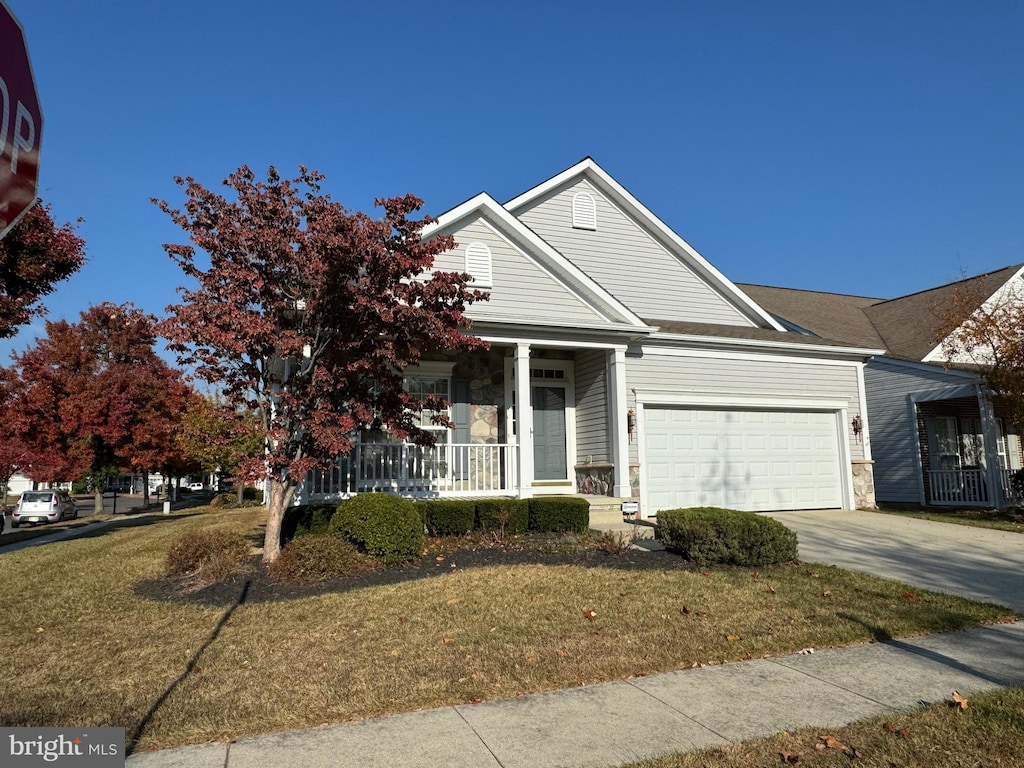 view of front facade featuring covered porch, a front yard, and a garage