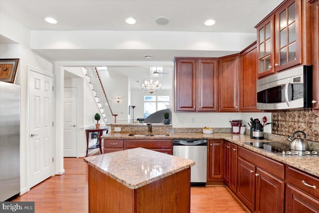 kitchen featuring a kitchen island, stainless steel appliances, sink, light stone countertops, and light hardwood / wood-style floors