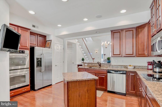 kitchen with sink, a center island, light hardwood / wood-style floors, stainless steel appliances, and pendant lighting