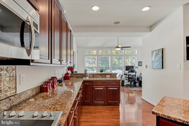 kitchen with kitchen peninsula, ceiling fan, light stone countertops, light hardwood / wood-style flooring, and black electric stovetop