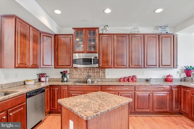 kitchen with light stone countertops, stainless steel appliances, and light wood-type flooring