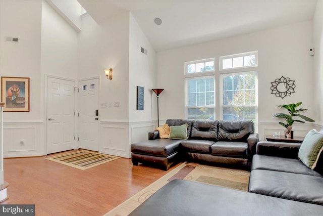 living room with wood-type flooring, high vaulted ceiling, and a skylight