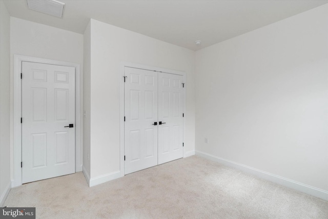 unfurnished bedroom featuring light colored carpet and a closet