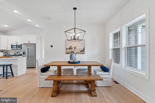 dining room featuring a chandelier, vaulted ceiling, and light hardwood / wood-style floors