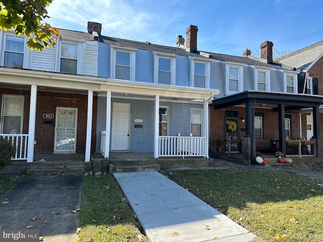 townhome / multi-family property with a front lawn and covered porch