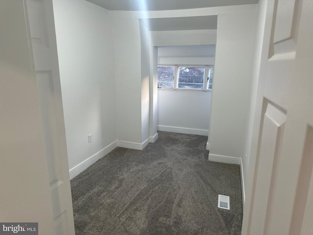 hall with dark colored carpet