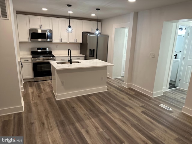 kitchen featuring a center island with sink, stainless steel appliances, dark hardwood / wood-style flooring, pendant lighting, and sink