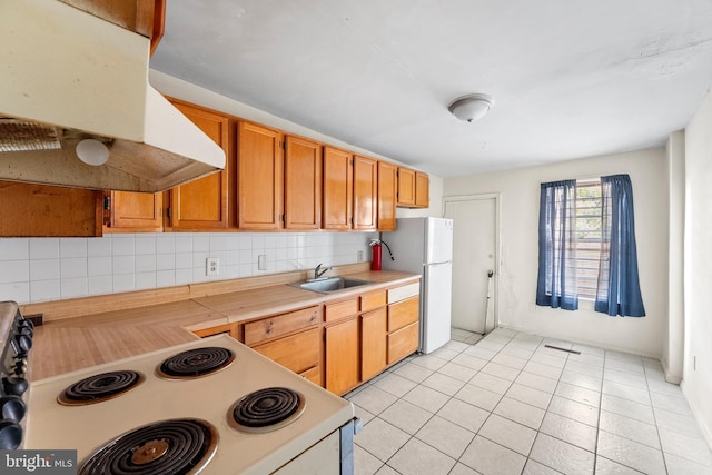 kitchen featuring tasteful backsplash, light tile patterned flooring, sink, ventilation hood, and white appliances