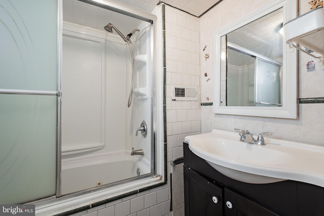 bathroom featuring vanity, tile walls, and combined bath / shower with glass door