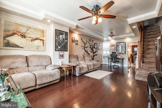 living room featuring ornamental molding, dark wood-type flooring, ceiling fan, and a raised ceiling