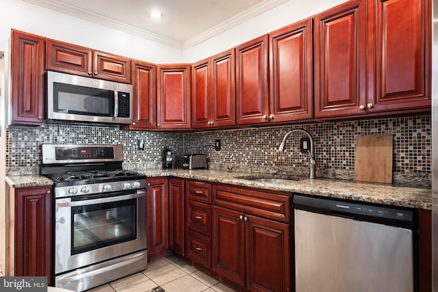 kitchen with light stone counters, stainless steel appliances, ornamental molding, and light tile patterned floors