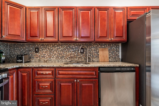 kitchen featuring light stone counters, appliances with stainless steel finishes, sink, and decorative backsplash