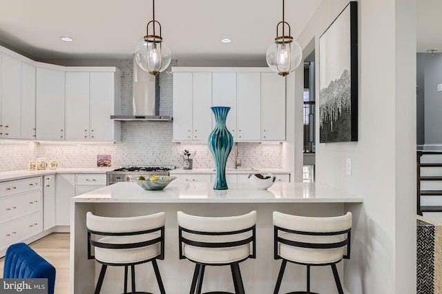 kitchen featuring a sink, stove, light wood-style flooring, wall chimney exhaust hood, and stainless steel dishwasher