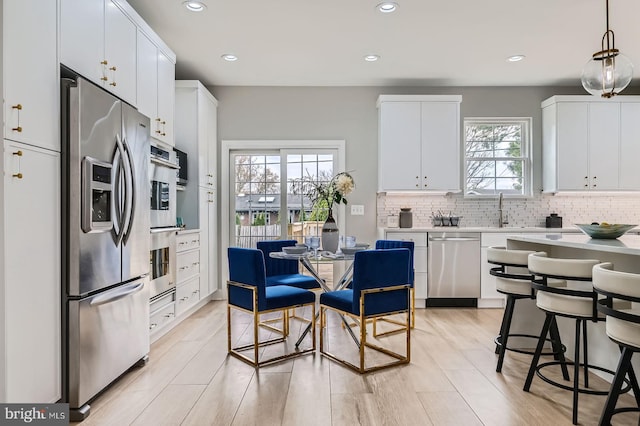 kitchen featuring baseboards, light wood-type flooring, white cabinets, and stainless steel appliances