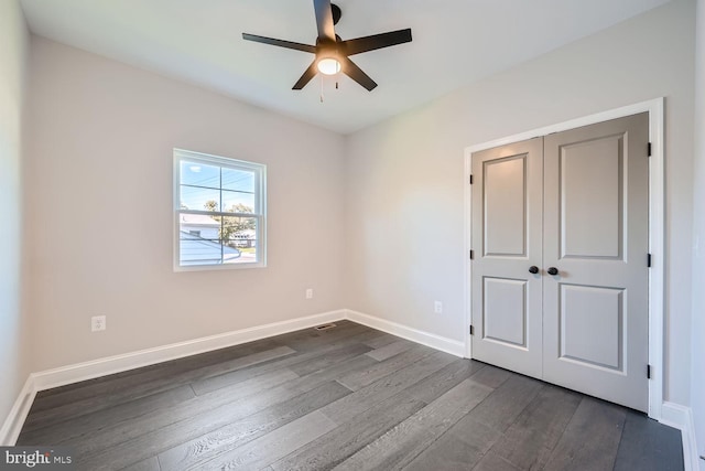 unfurnished bedroom with ceiling fan, a closet, and dark hardwood / wood-style flooring