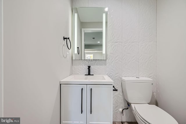 bathroom with toilet, decorative backsplash, and vanity