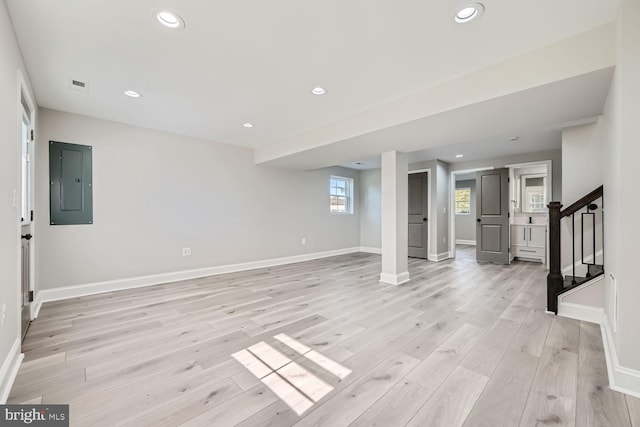 basement with light hardwood / wood-style floors and electric panel