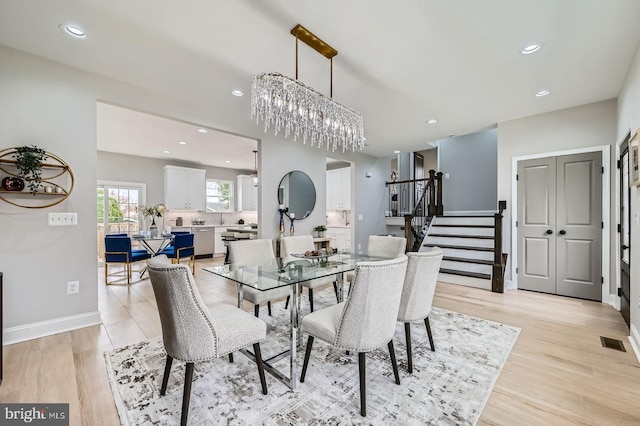 basement featuring visible vents, light wood-style flooring, stairs, and baseboards