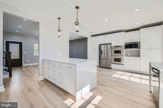 kitchen featuring appliances with stainless steel finishes, hanging light fixtures, white cabinetry, light stone counters, and light hardwood / wood-style flooring