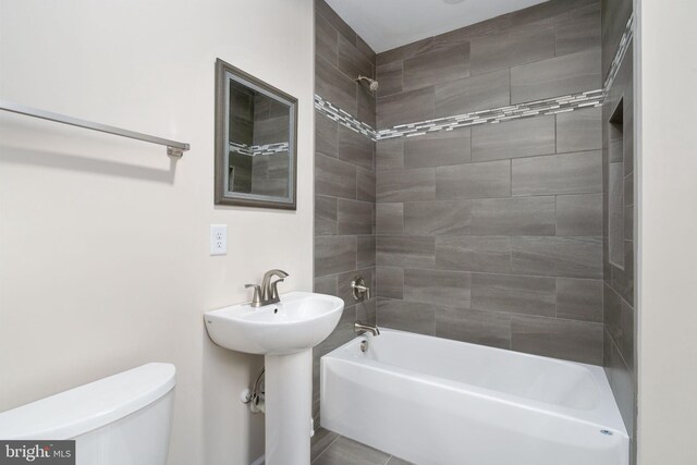 bathroom with toilet and tiled shower / bath