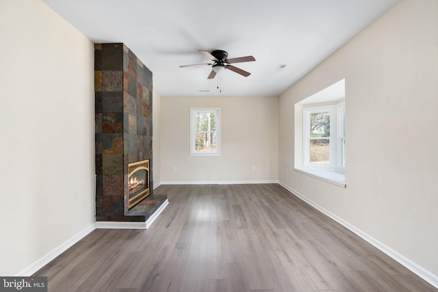 unfurnished living room featuring a large fireplace, light hardwood / wood-style flooring, and ceiling fan